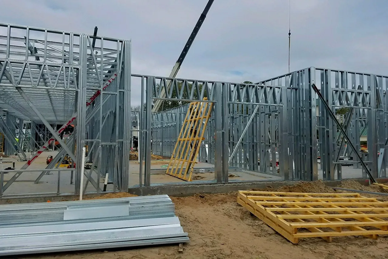 Prepanelized cold-formed steel wall panels standing on a slab, crane behind